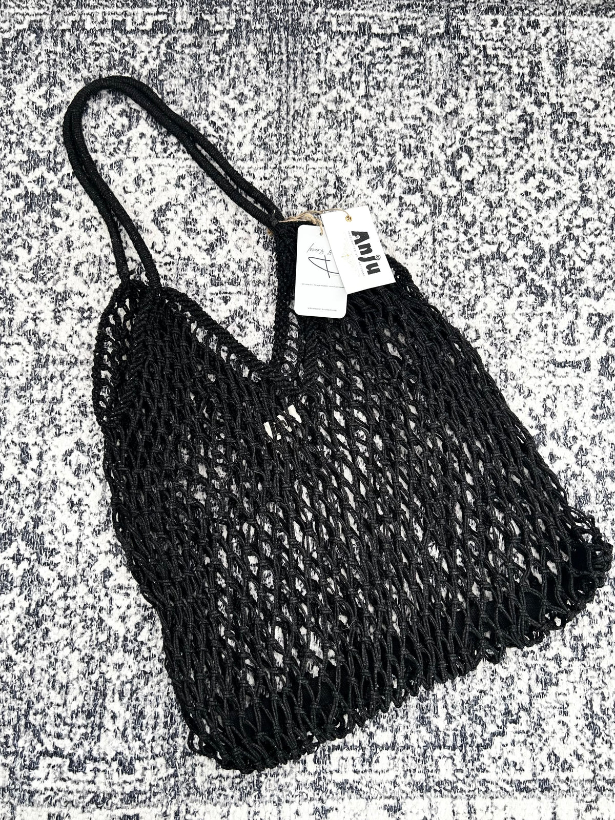 Black mesh bag with a tag on a textured gray background
