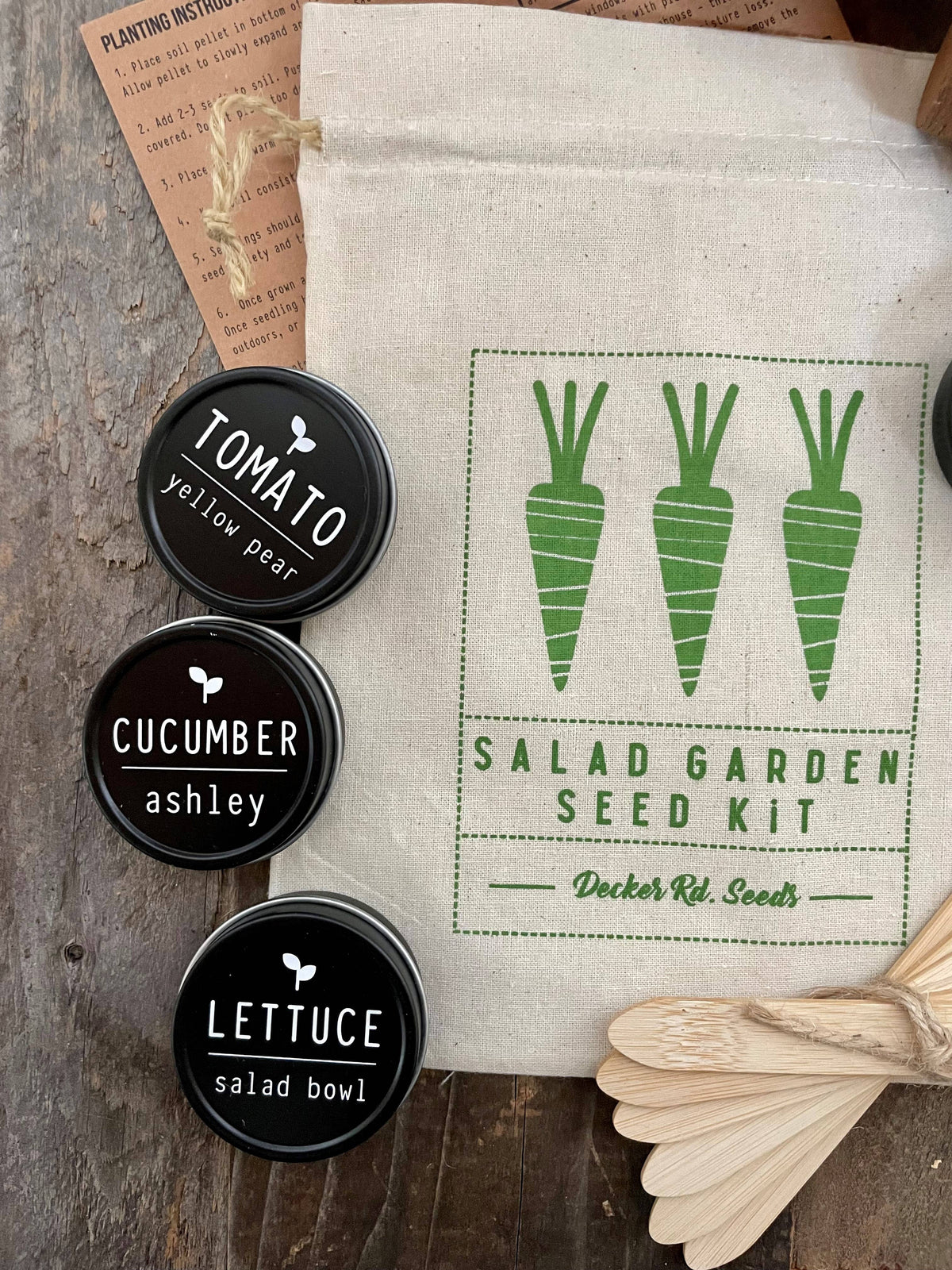 Salad garden seed kit with labels for tomato, cucumber, and lettuce on a wooden surface.