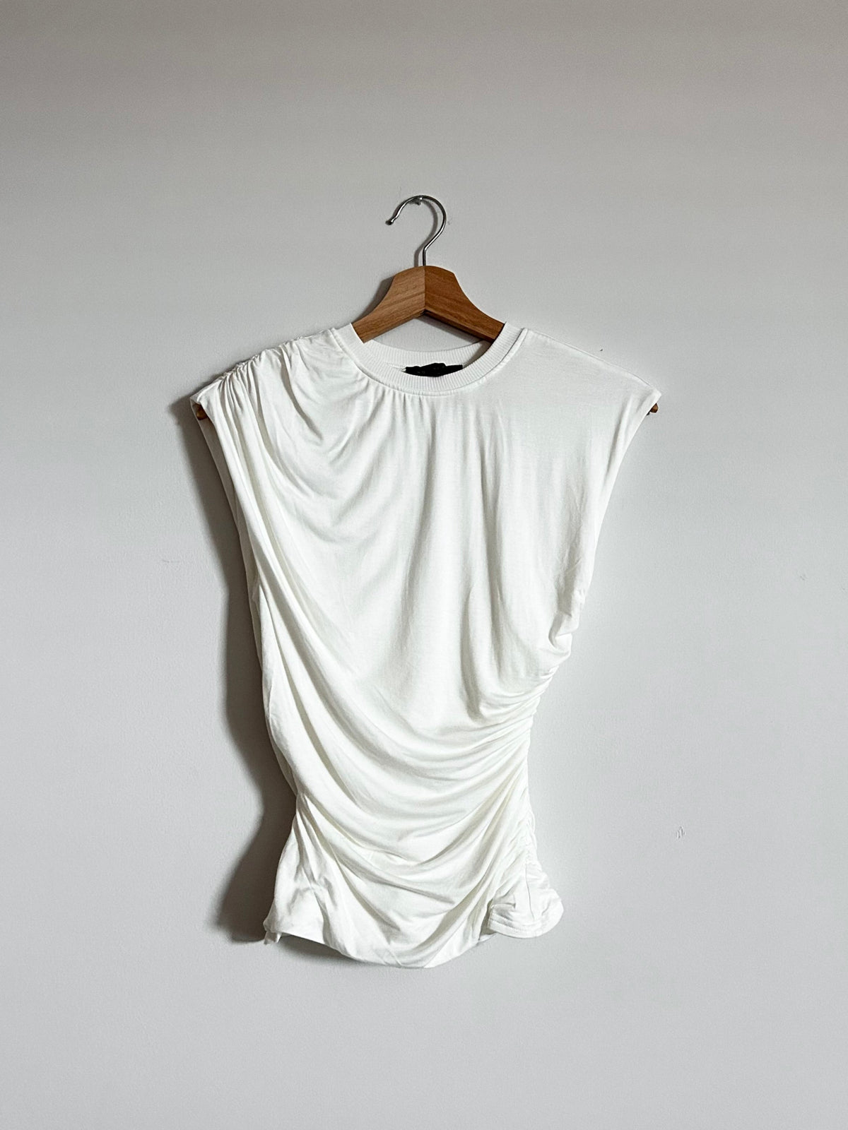 White sleeveless top on a hanger against a plain background

Double layered sleeveless drape detail top

Ribbed contrast round neckline

Ruching on one shoulder

Diagonal draping

Ruching on the sides

Standard length

Good stretch