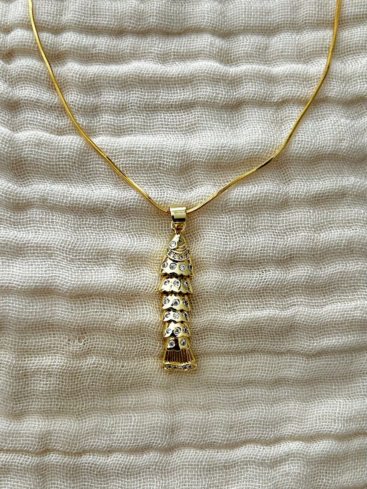 Gold necklace with a textured pendant on a textured beige fabric background

Unique Articulate Fish Design Pendant Necklace

Pendant

Material: Brass, 24K&nbsp;Gold Filled, Cubic Zirconia&nbsp;

Size: 7.9mm x 34.8mm x 5.1mm&nbsp;



Chain

Material: 24K Gold Plated

Style: Cocoon Chain

Length: 18 Inches Width: 0.8mm

Clasps: Spring Ring