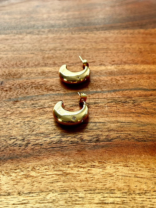 Gold crescent moon earrings on a wooden surface