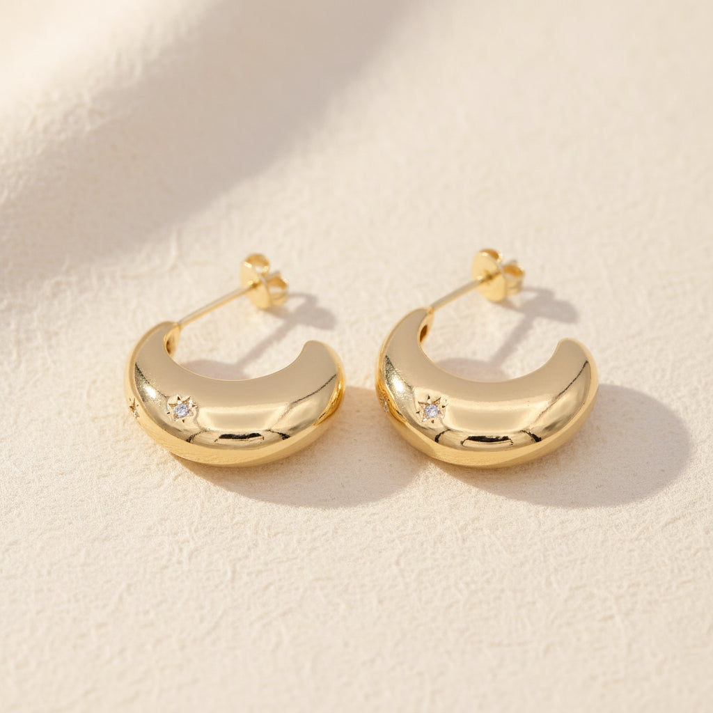 Gold hoop earrings with small CZ faux diamonds on a beige background