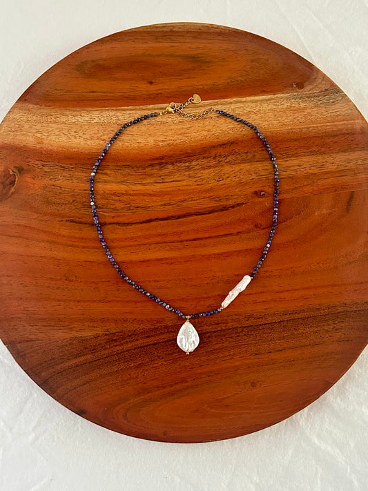 Necklace with blue beads and a pearl pendant on a wooden surface