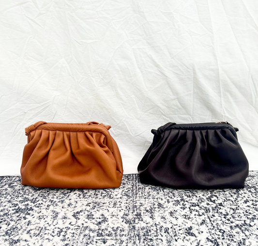 Two handbags, one brown and one black, on a textured surface with a white background.