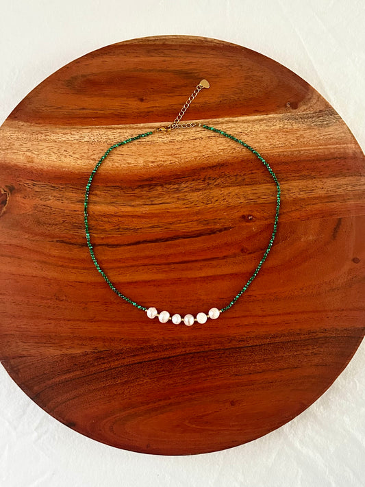 Necklace with green beaded chain and pink beads on a wooden surface