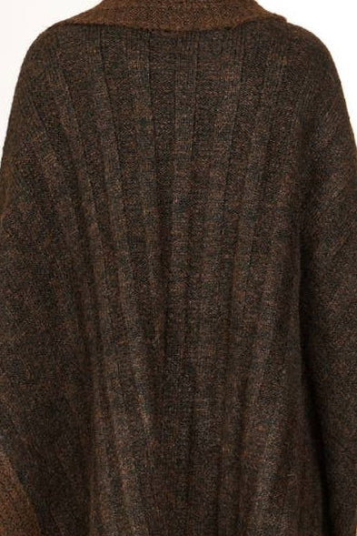 A woman shown from the back wearing a dark brown textured knit poncho over a beige wide-leg skirt, against a plain white studio background.